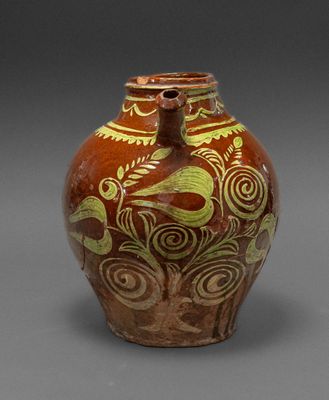 une image représentant un vase marron et vert posé sur une surface grise