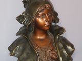 bronze bust of a woman with a hat on a stand