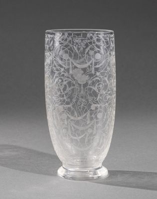 an etched glass vase sitting on top of a table next to a gray wall