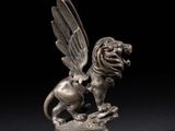 une figurine en argent représentant un lion ailé posé sur un rocher