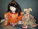 two dolls sitting next to each other on a couch