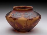 a brown vase with flowers on it on a white surface