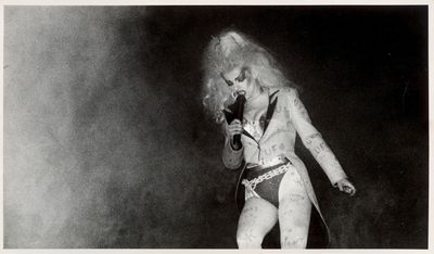 black and white photograph of a woman with long hair singing into a microphone