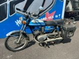 une moto bleue garée devant un mur recouvert de graffitis