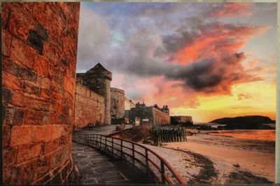 photo d'un coucher de soleil sur une plage, avec un château en arrière-plan