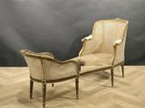 a white and gold chaise lounger sitting on top of a wooden floor