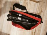 a red bag with three tripods in it on a wooden floor