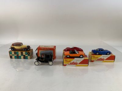 four toy cars are lined up in a row on a white surface