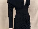 La robe est noire, à manches longues et avec un décolleté en V.
