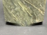 a green marble block on a gray surface