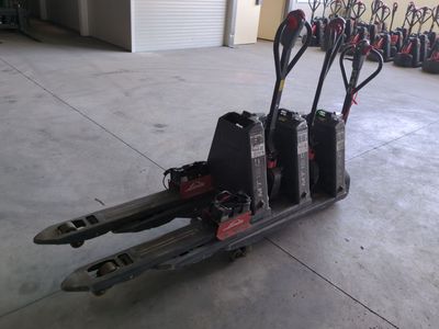 Plusieurs paires de skis et de bâtons de ski sont empilés sur un chariot dans un garage.
