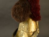 helmet with fur on top of it on a stand against a black background