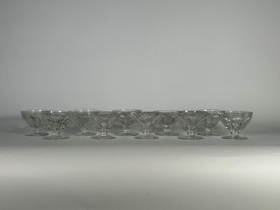 six verres à vin en cristal posés sur une surface blanche, avec une lumière en arrière-plan