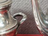 une théière en argent et une théière en argent posées sur un napperon rouge
