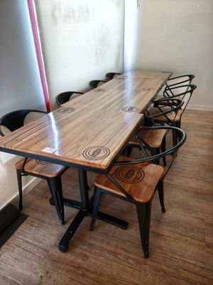 une longue table entourée de quatre chaises, avec un canapé à l'arrière-plan