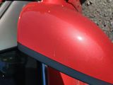 a close up of a red motorcycle mirror on the side of the road
