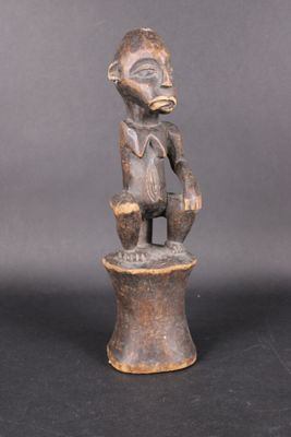 une photo représentant la statue d'un homme assis sur un tabouret