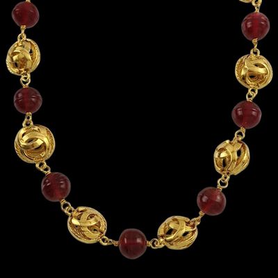 un collier en or orné de perles de verre rouges et muni d'un fermoir en or