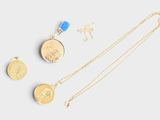 three gold necklaces and a coin on a white surface