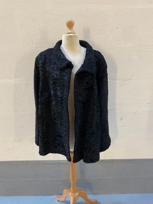une veste noire posée sur un mannequin devant un mur blanc