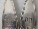 three silver spoons with engraved names on them sitting on a table