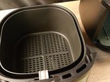 une friteuse à air chaud posée sur un plan de travail, à côté d'une poêle