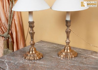 deux lampes posées sur une table, avec un rideau derrière elles