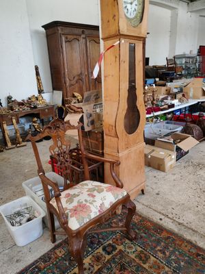 une grande horloge de parquet trônant dans une pièce où se trouve un fauteuil