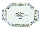 a blue and white plate with a basket of fruit on it