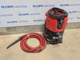 a red and black vacuum and a hose on the ground