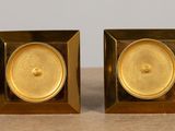 two gold colored candles sitting on a wooden table