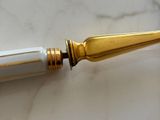 a white and gold pen sitting on a marble table