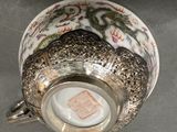 a silver cup with a dragon on it on a table