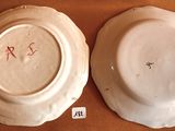 two white plates with red writing on them sitting on a table