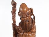 wooden statue of an old man holding a staff and wearing a hat