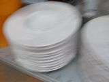 several white plates are stacked on a tray in a kitchen