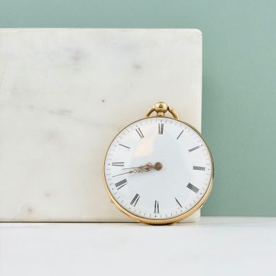 un bloc de marbre blanc sur lequel est posée une horloge dorée