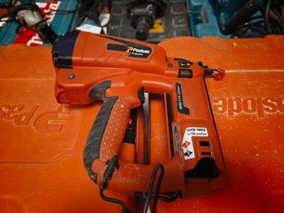a corded nail gun sitting on top of an orange box
