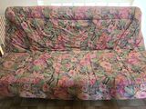 un canapé-futon recouvert d'une housse à motifs floraux colorés