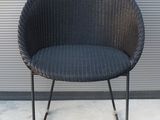 une chaise en osier noir avec une structure en métal noir
