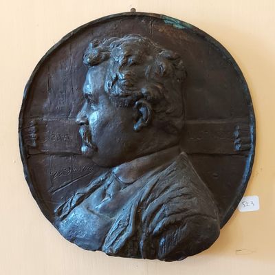 une plaque en bronze représentant un homme moustachu, fixée au mur