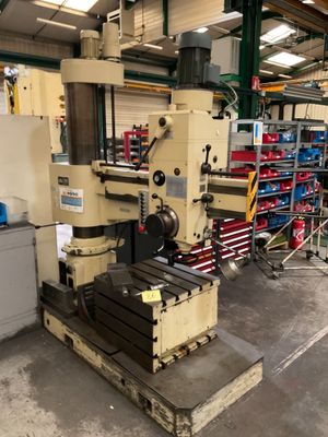 Une grande machine est posée dans un entrepôt, avec d'autres machines en arrière-plan.