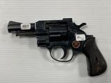 un gros plan d'un revolver posé sur une table, avec une étiquette dessus