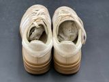 pair of beige sneakers with laces on the soles on a black surface