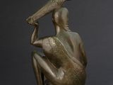bronze statue of a woman sitting on a rock with a bottle in her hand