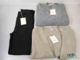 three pairs of sweaters and pants sitting on a white surface