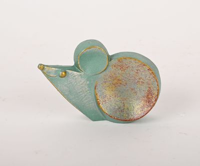 une petite figurine de souris verte et dorée posée sur une surface blanche