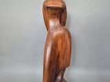 wooden sculpture of a woman sitting on a rock with her back to the camera