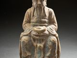 une vieille statue représentant un homme assis sur une chaise, tenant un bol