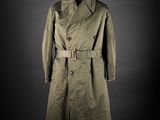 un trench-coat vert posé sur un mannequin, sur fond noir
